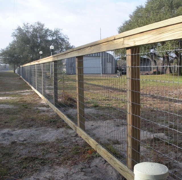 Treated wood post and hog wire farm perimeter fence — East Tennessee rural property